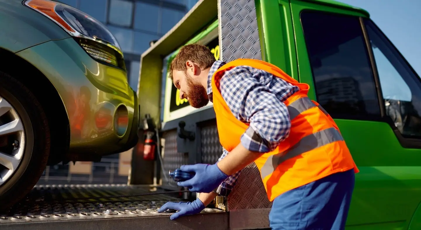  A worker securing a car onto a towing truck at Stratford, E15 for White Recovery.