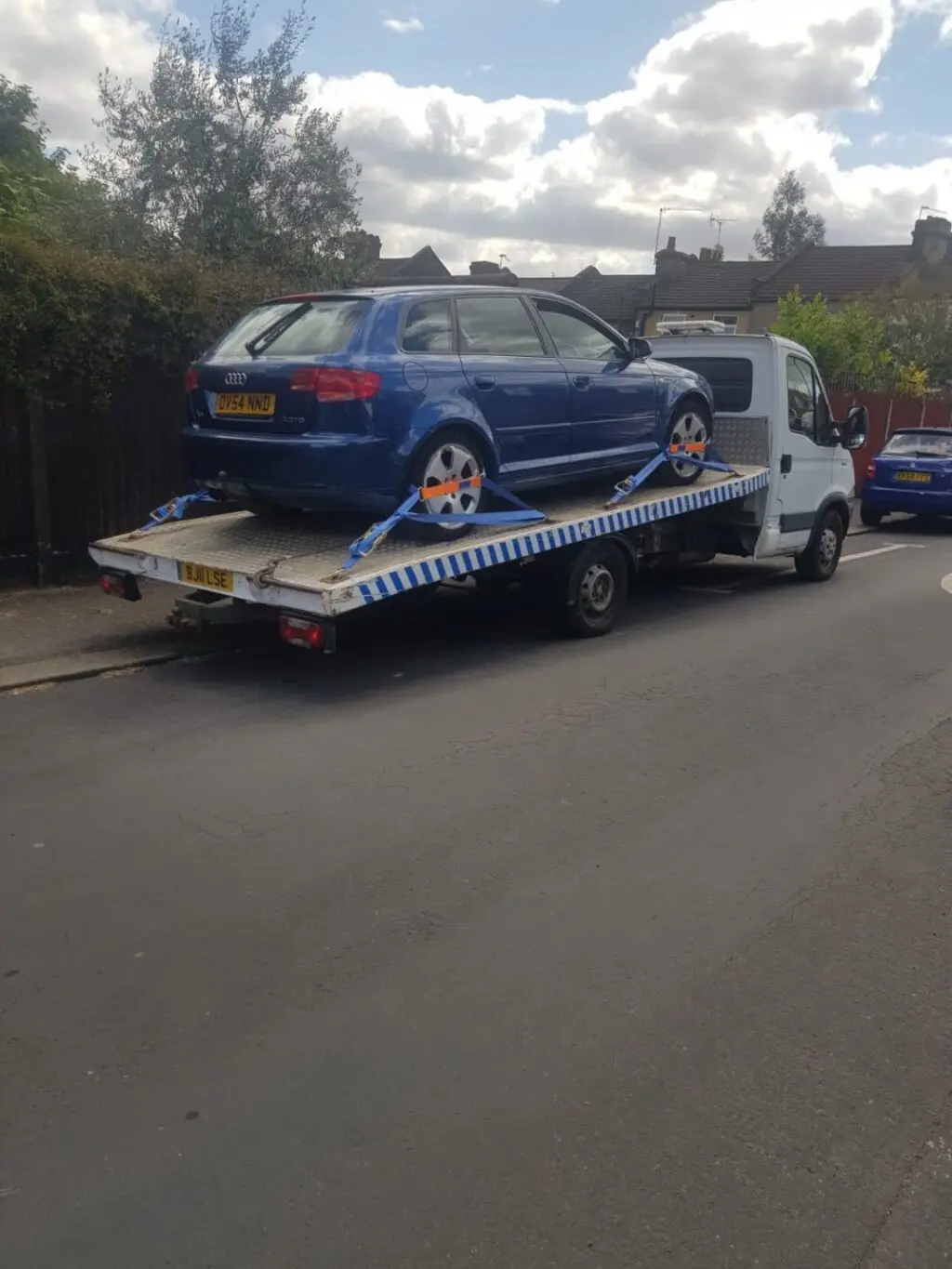 A blue car securely strapped on a flatbed recovery truck in Marylebone, W1. White Recovery providing professional towing and breakdown services.