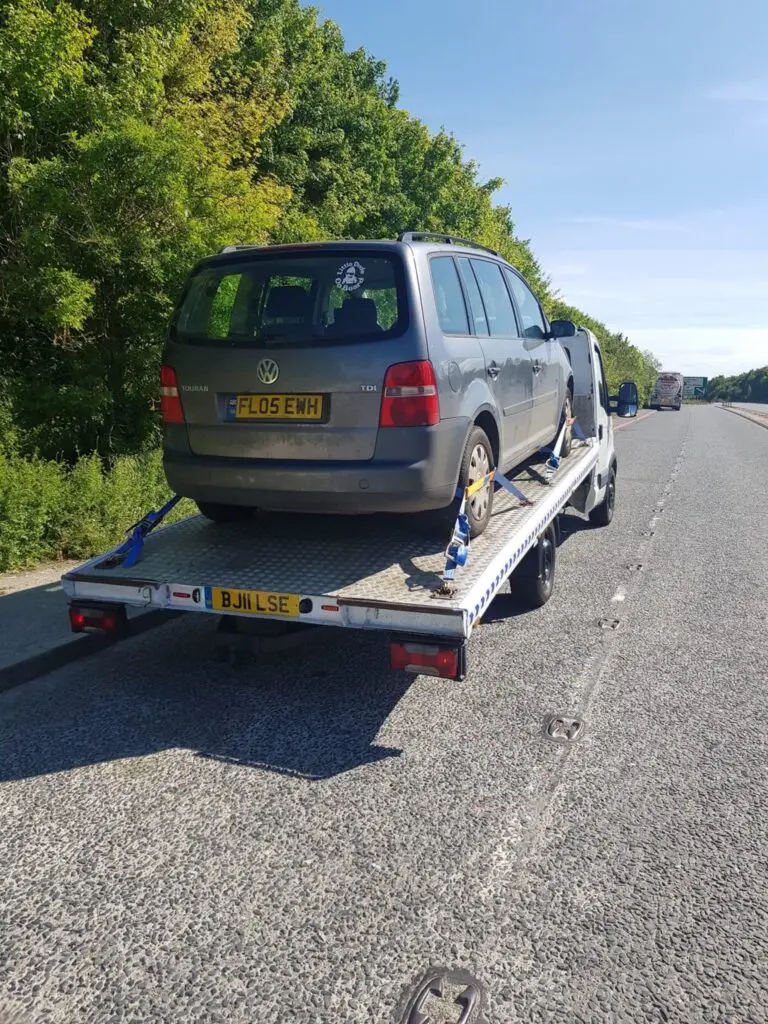 A grey car securely strapped on a flatbed recovery truck in Acton, W3. White Recovery providing expert towing and breakdown services.