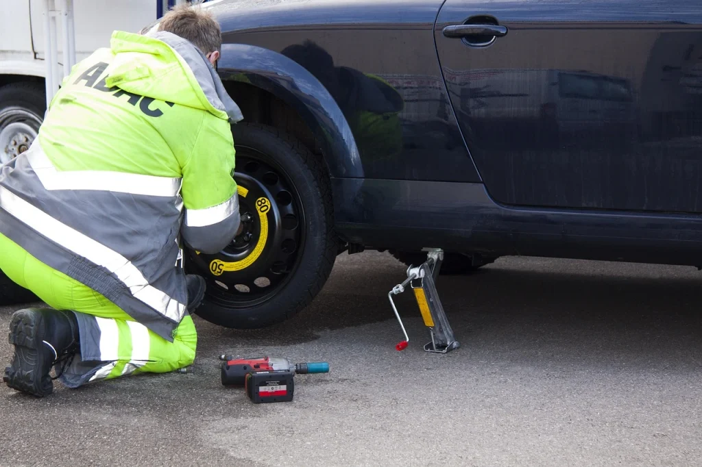 Mechanic performing a tyre change during roadside assistance on a car