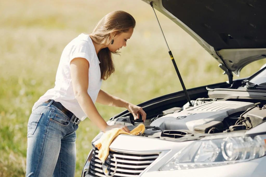 Driver checking an overheated car engine at the roadside before calling breakdown recovery service in Barking
