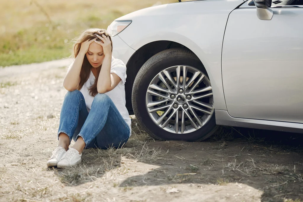 Woman beside broken down car waiting for White Recovery vehicle assistance