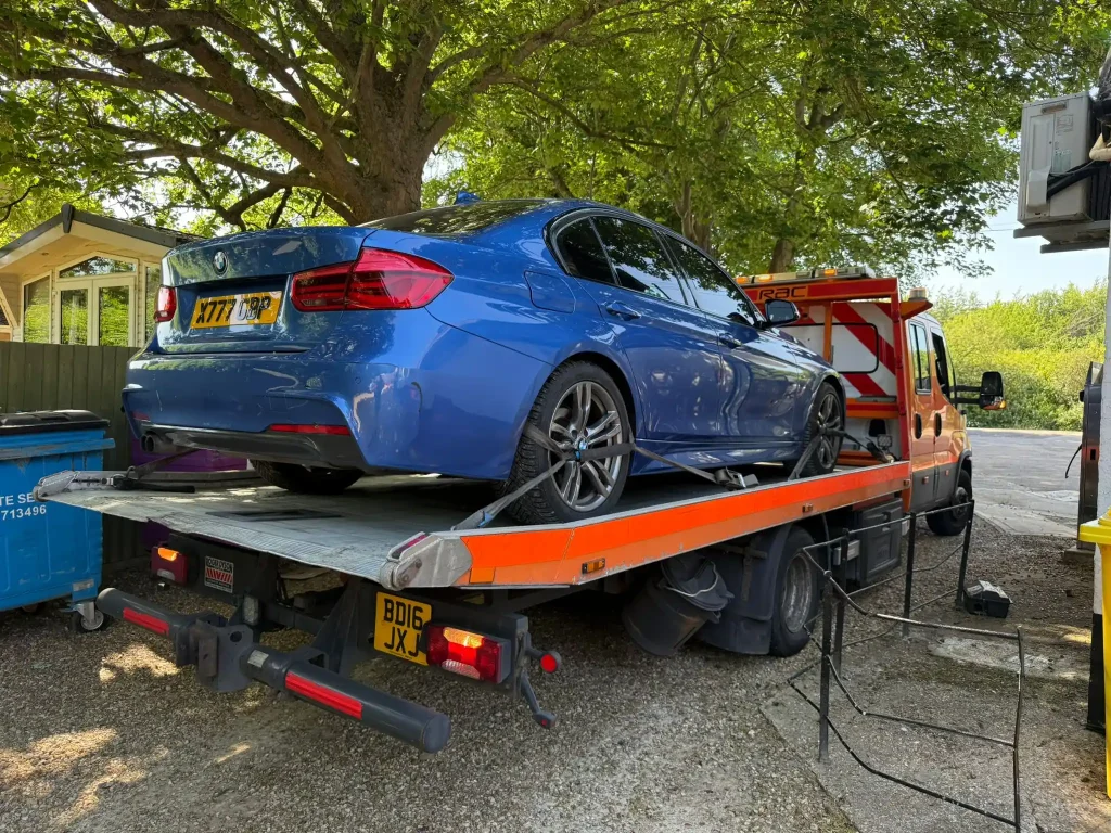 24-hour car and van recovery service in Hammersmith London by White Recovery transporting a blue BMW on a flatbed recovery truck