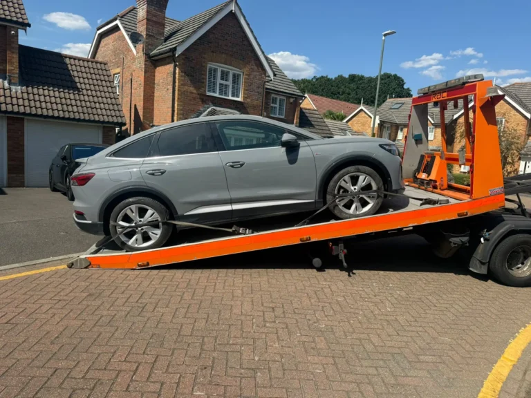 White Recovery flatbed truck transporting a grey Audi during vehicle recovery in Gidea Park, London.