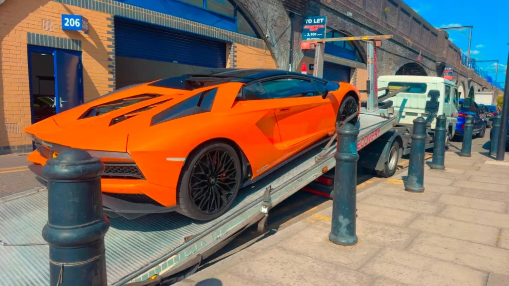 Orange Lamborghini secured on a flatbed tow truck for professional car recovery.