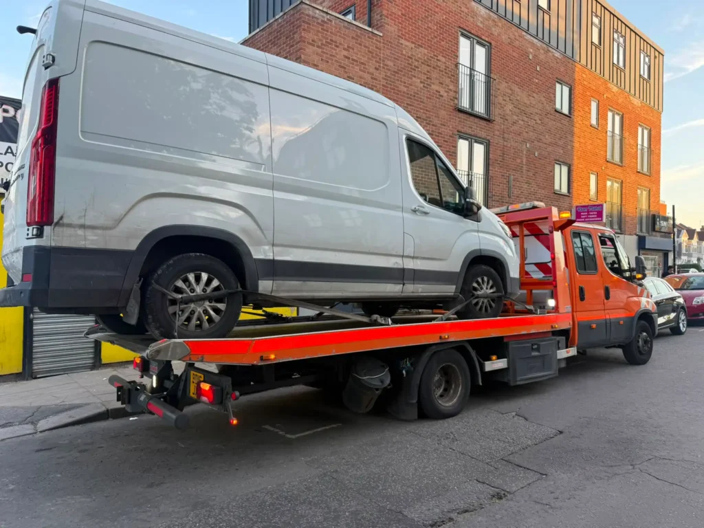 White commercial van secured on a flatbed recovery truck for van recovery in Croydon.