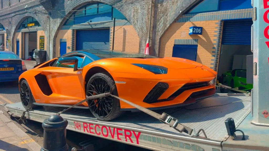 Orange Lamborghini securely loaded onto a flatbed recovery truck for professional vehicle recovery.