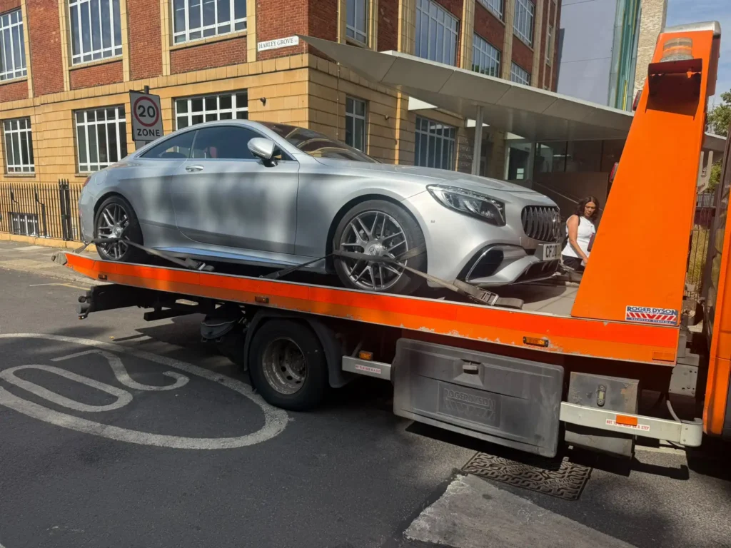 Silver Mercedes secured on a WhiteRecovery flatbed tow truck for safe vehicle transportation.